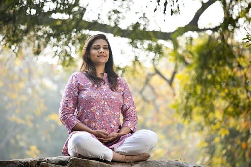 Beautiful woman meditating position at park